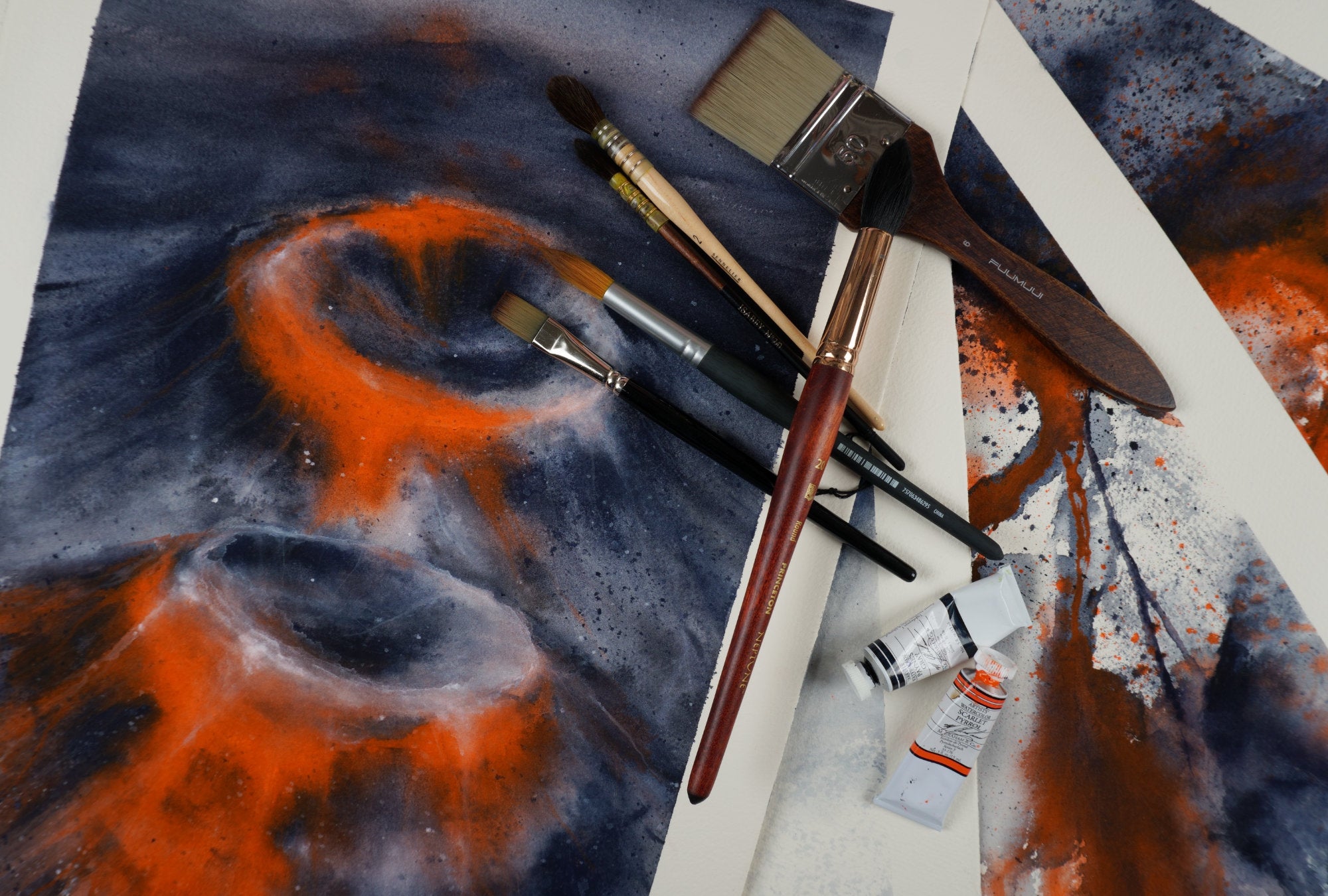 Watercolour brushes and M. Graham watercolour paints scattered on the staggered artworks Rings of Fire, Red Zone, River of Death and At 1000 Degrees, part of The Magma Collection by Haidi Hildemore.